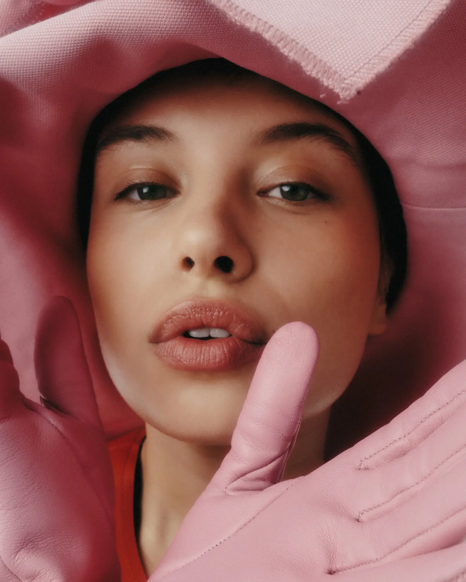 Close portrait of a person framed by pink gloves and fabric
